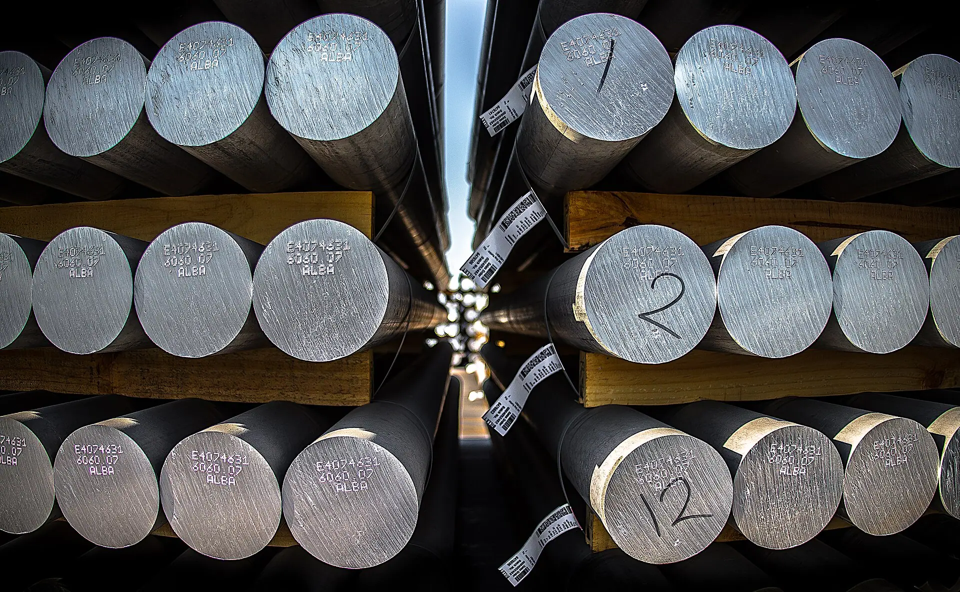 Circular ends of stacked aluminum billets separated by timber spacers.