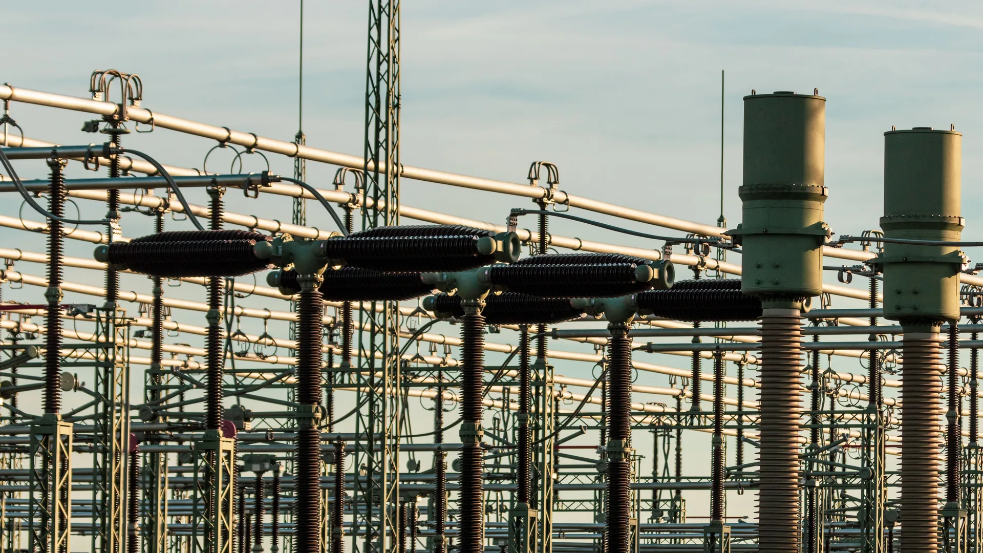 High-voltage switchyard equipment, insulators and bus conductors at an electrical substation.