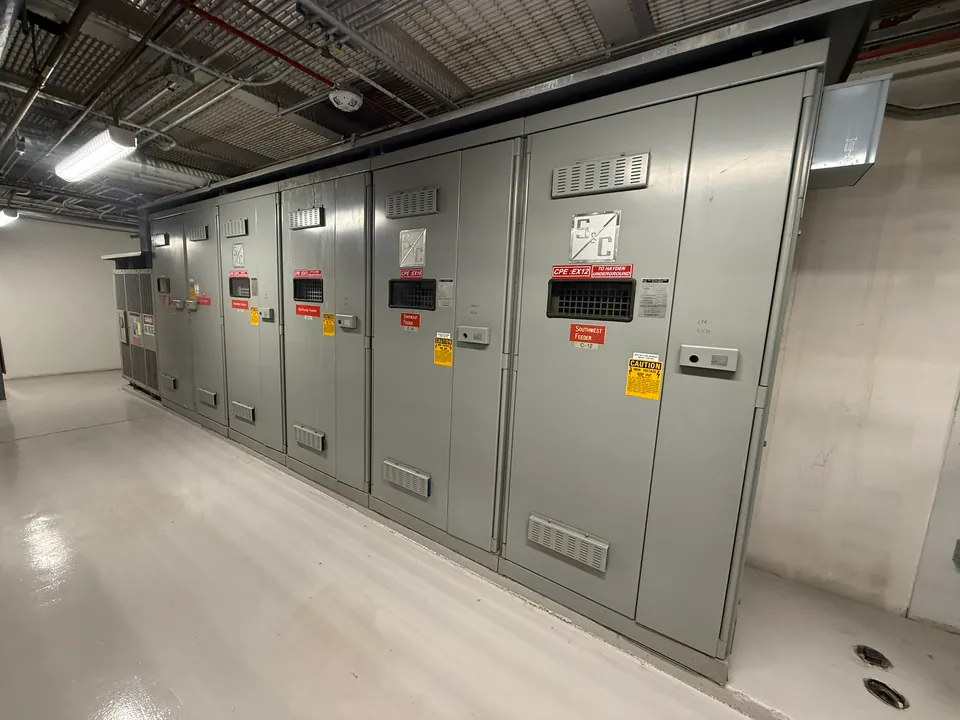 Indoor lineup of metal-enclosed electrical switchgear cabinets.