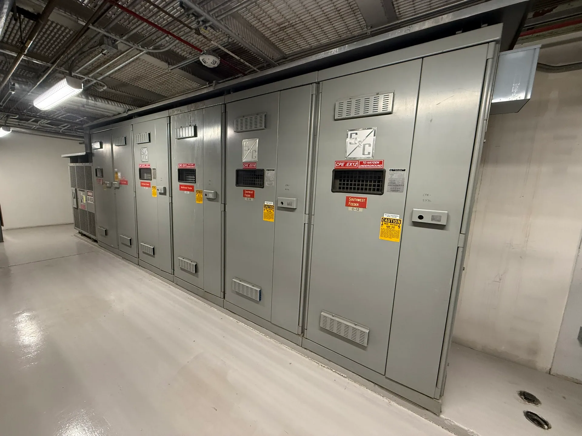Indoor lineup of metal-enclosed electrical switchgear cabinets.